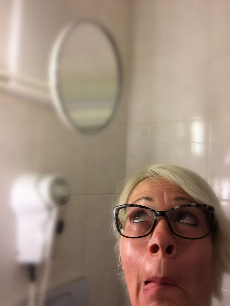 Frau im Badezimmer, dessen Spiegel zu hoch hängt